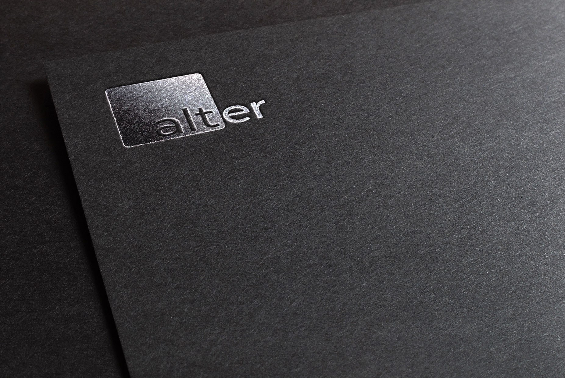 The Alter logo embossed in silver on black paper.